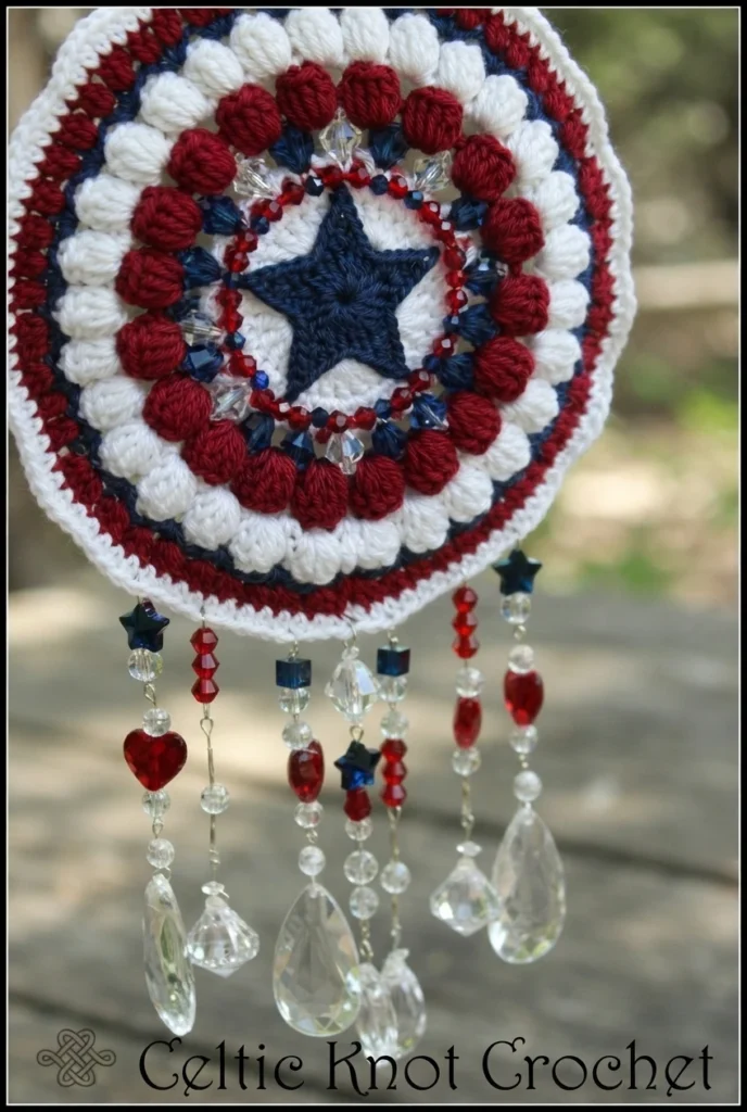 Red, white and blue crochet mandala with a blue star center and hanging clear, red and blue beaded strands