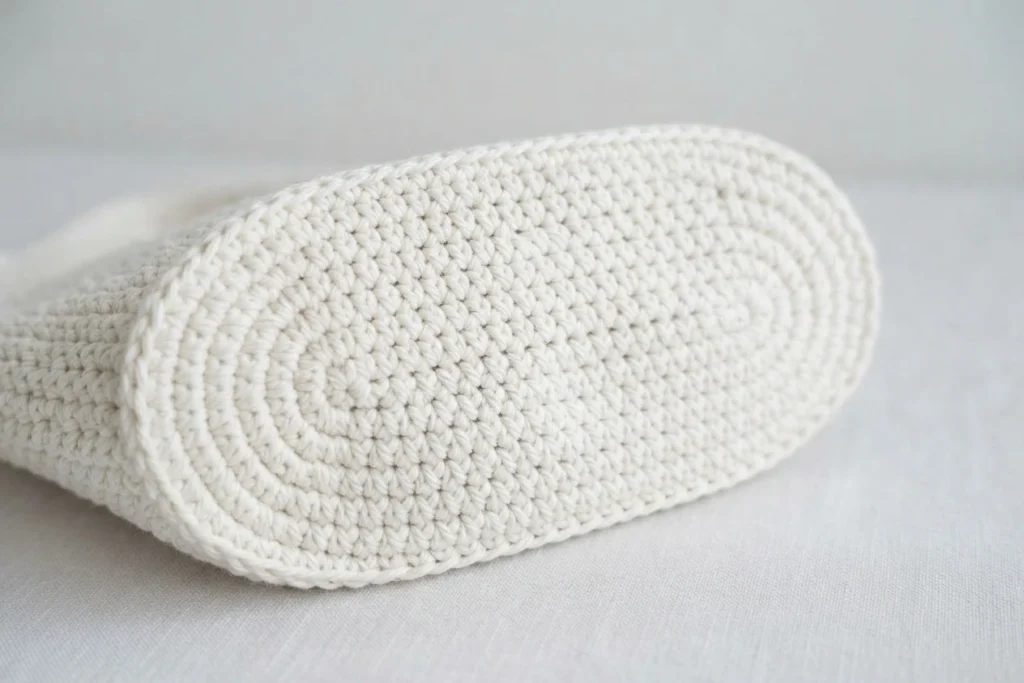 Close-up of a white crocheted oval tote base showing spiral rounds