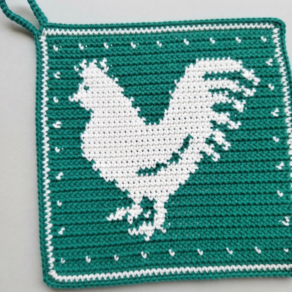 Green crocheted rooster potholder with white rooster motif, white border and hanging loop