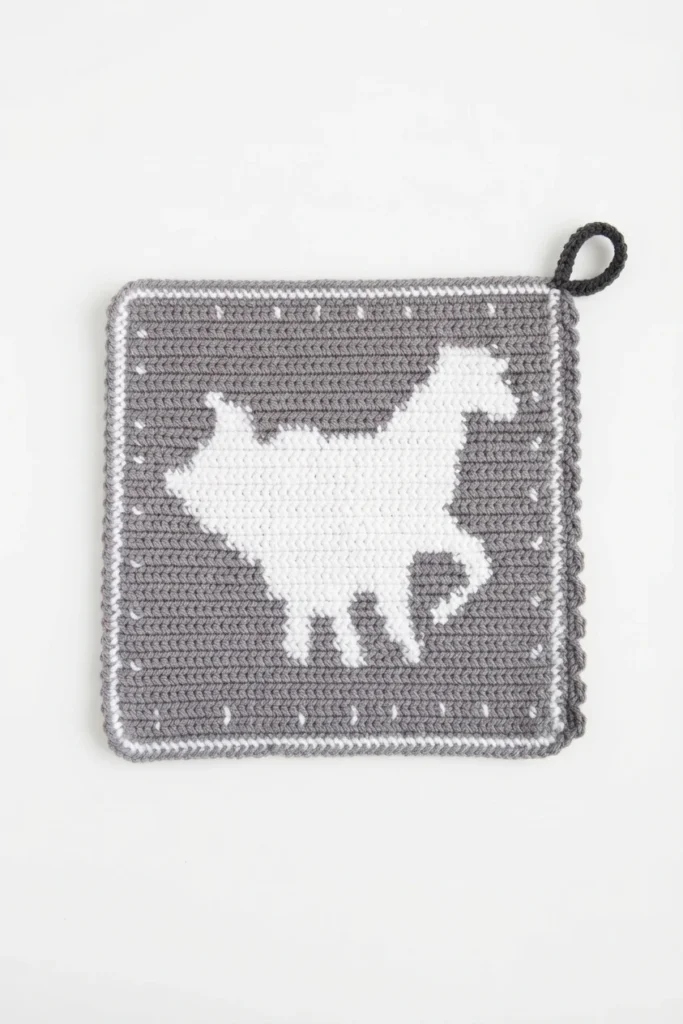 Grey crocheted square potholder with a white horse motif, a white border and a dark hanging loop on a plain white background