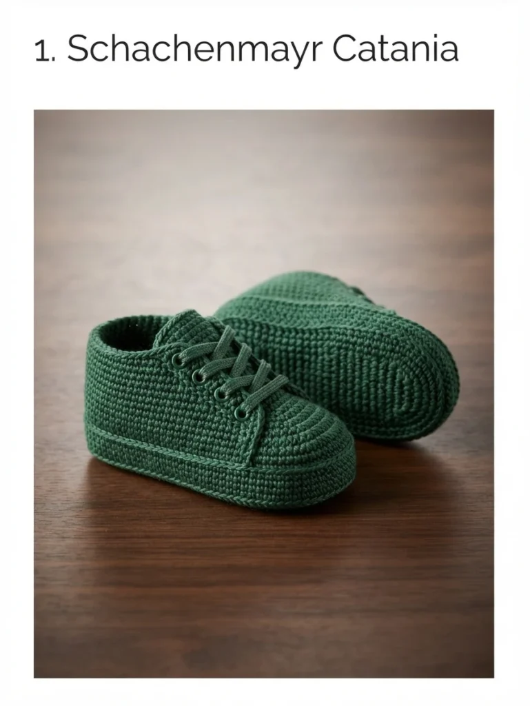 Pair of dark green crocheted baby sneakers with laces on a wooden surface
