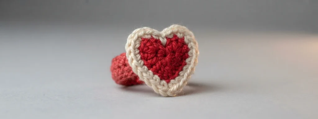 A crocheted heart ring with a red heart center, a white border and a red ring band.