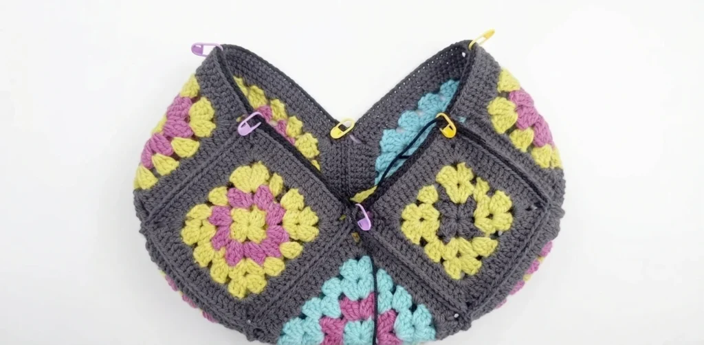 Granny squares arranged in a V shape with stitch markers before seaming